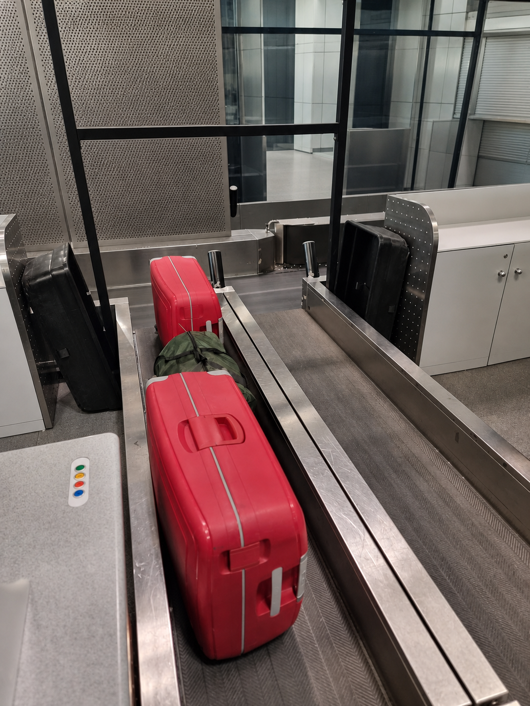 Two red hard-shell suitcases on an airport baggage belt